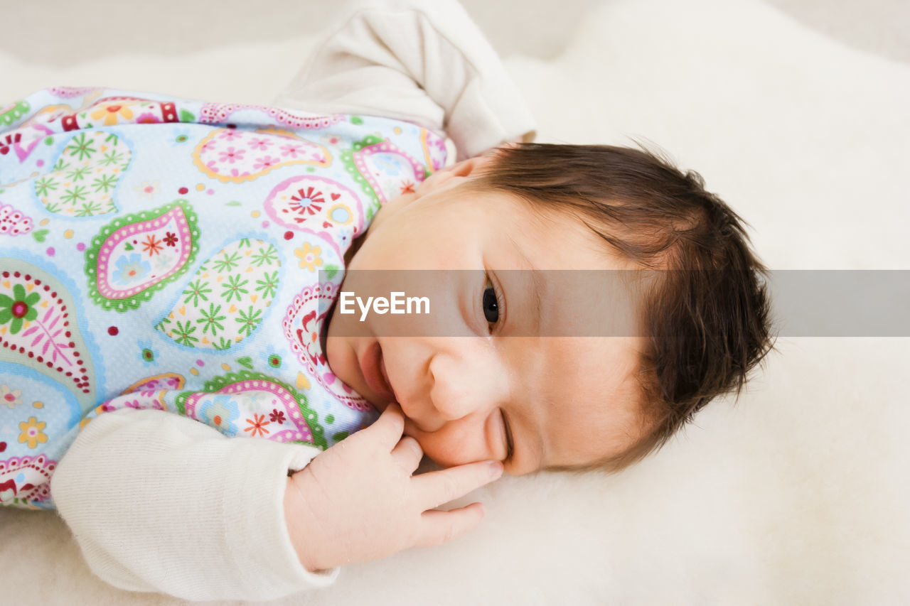 PORTRAIT OF CUTE BABY GIRL LYING ON BED