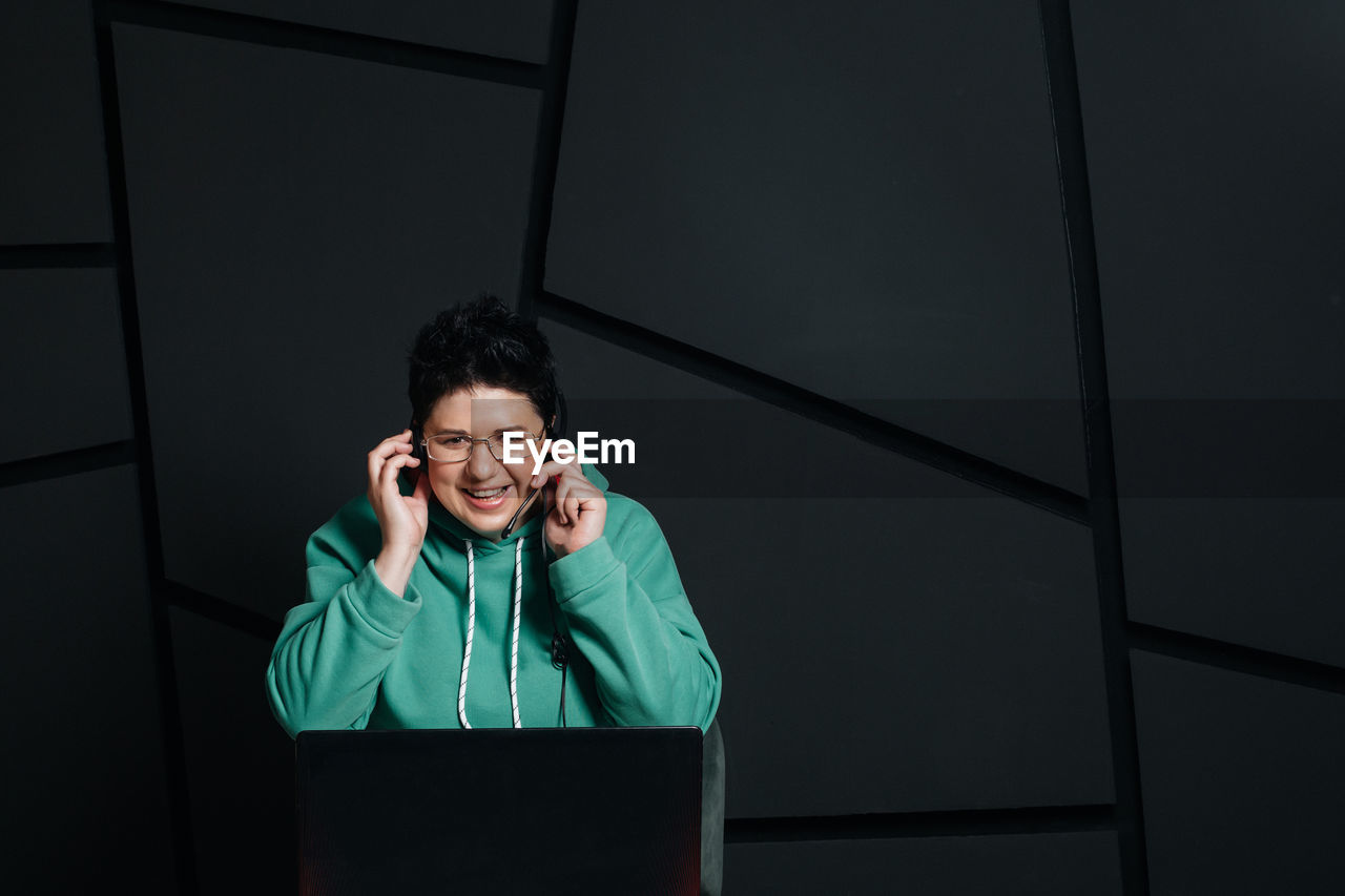 PORTRAIT OF A SMILING YOUNG MAN USING LAPTOP