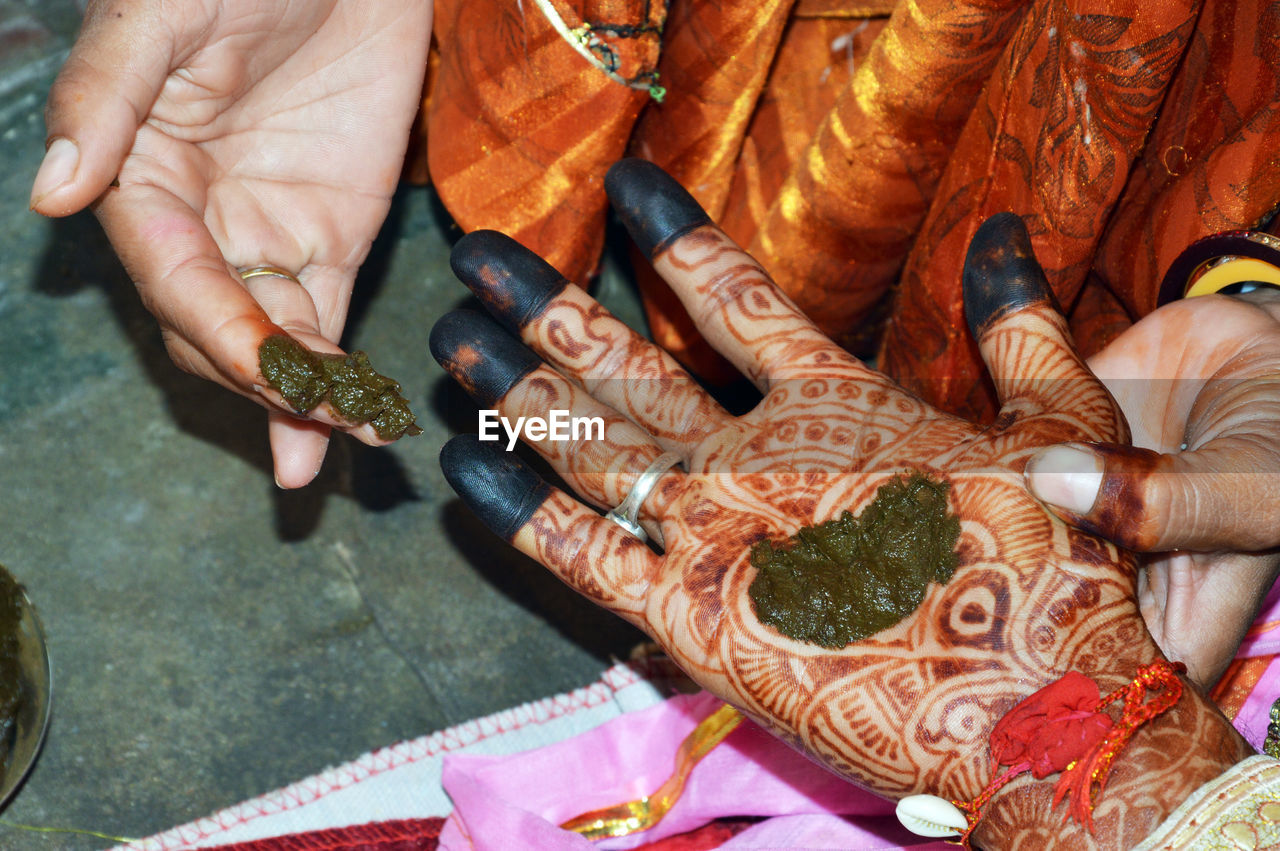 Woman put henna on groom hand to prepare indian wedding tradition called hast milap.