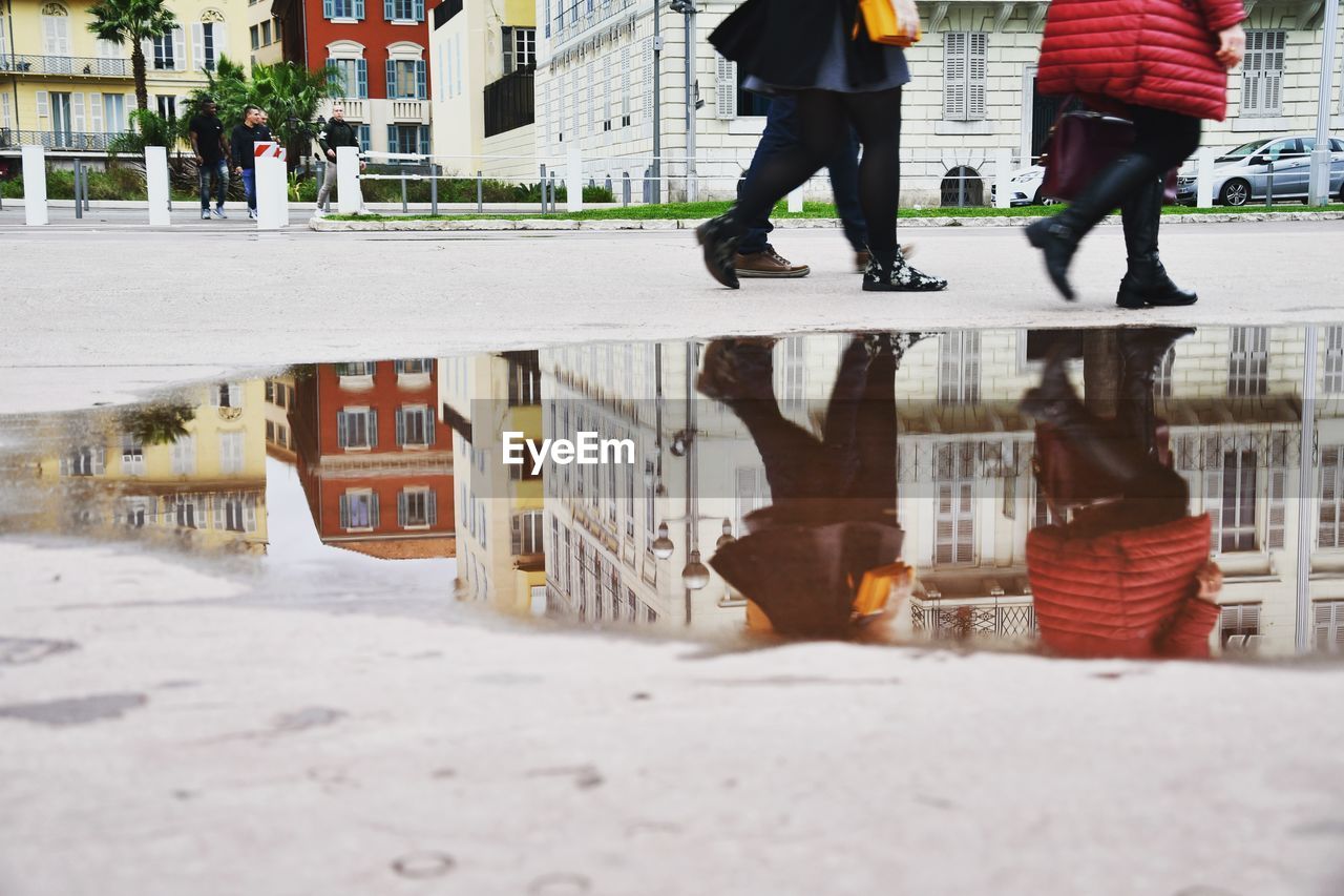 Low section of people walking on street in city