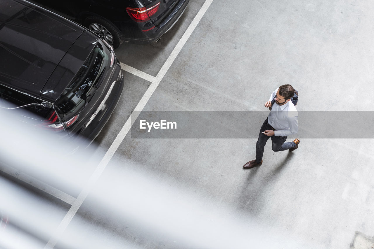 Young businessman with backpack on the go at parking garage