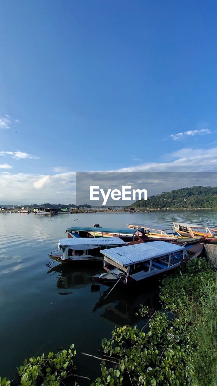 BOAT MOORED ON LAKE AGAINST SKY