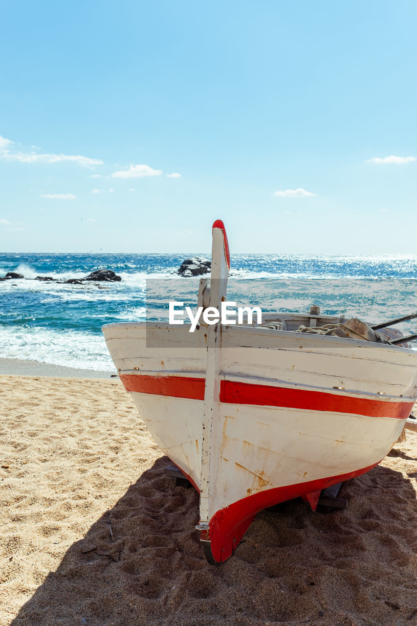 Fishing boat on beach against sky