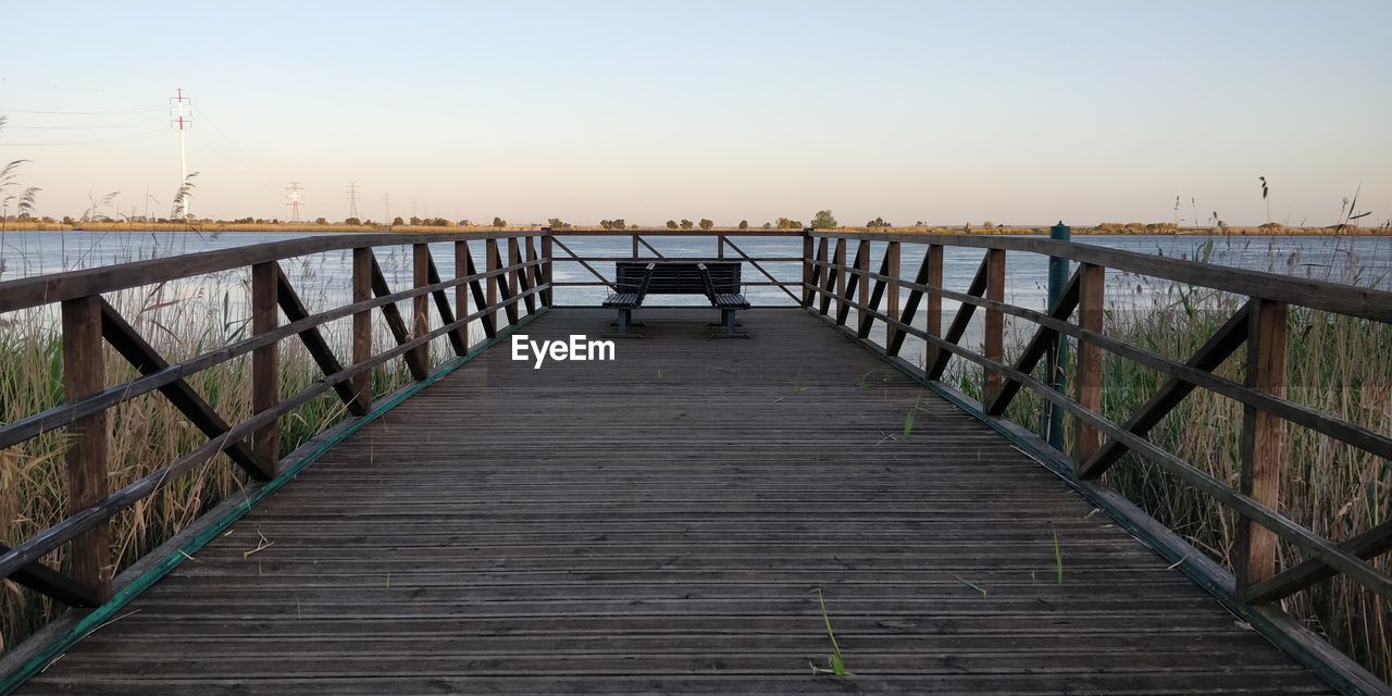 Pier over sea against sky during sunset