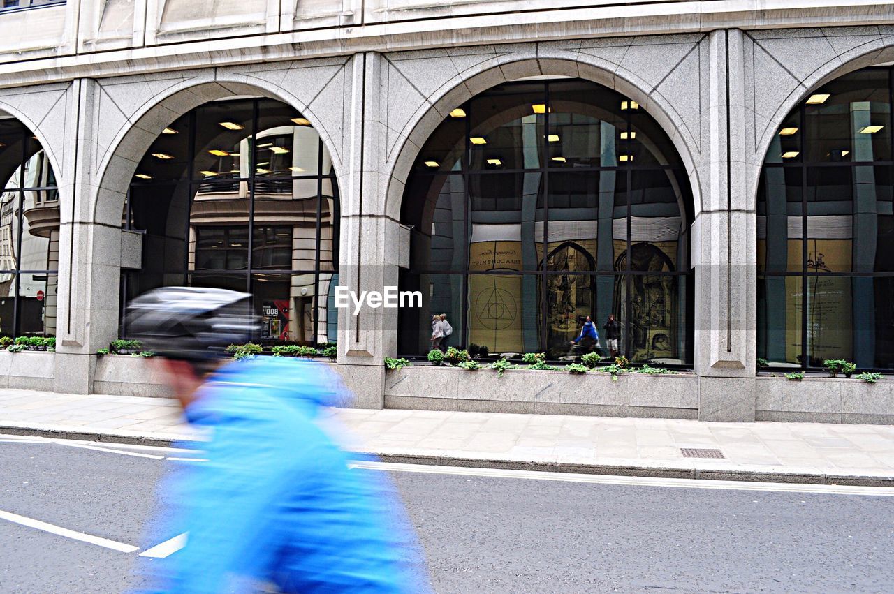 Blur image of man on city street against building