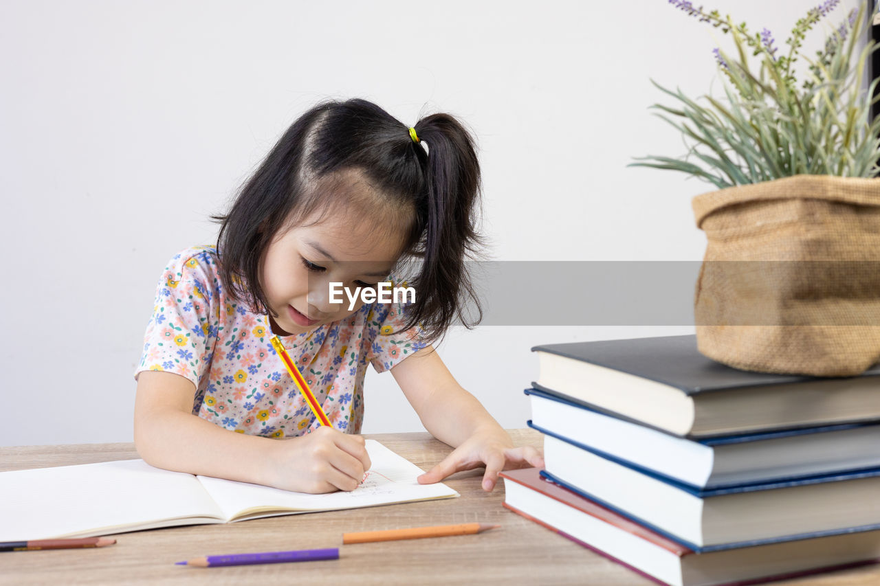 side view of girl playing with books on table at home