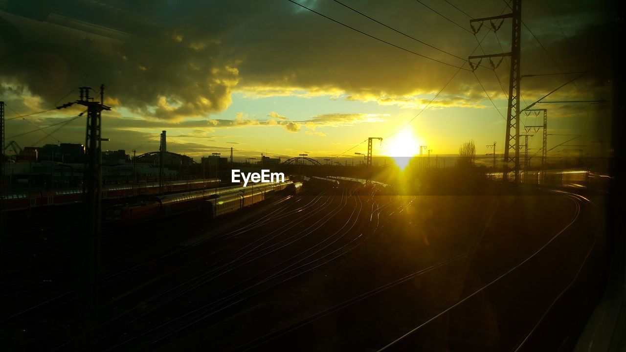 VIEW OF RAILWAY TRACKS AGAINST SUNSET SKY