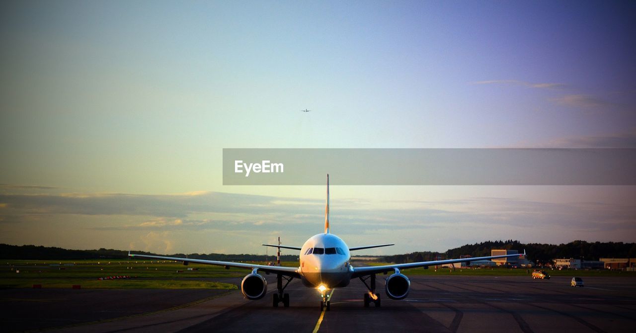 AIRPLANE ON RUNWAY AGAINST SKY DURING SUNSET