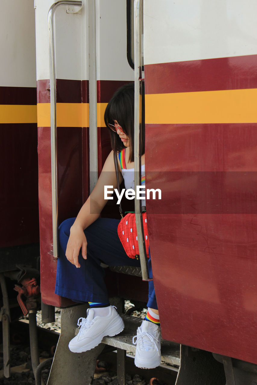 Young woman sitting at train entrance