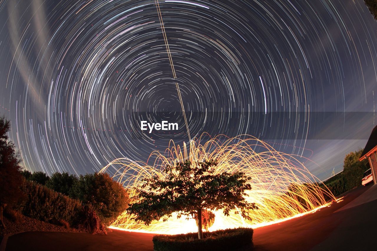 Firework display against star trails