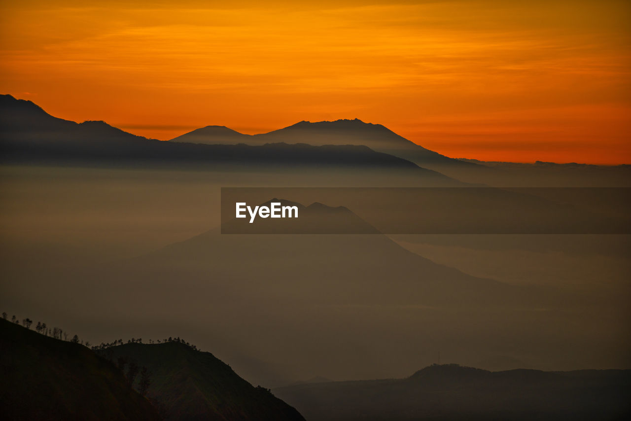 mountain, scenics - nature, beauty in nature, sky, sunrise, landscape, horizon, dawn, mountain range, environment, nature, tranquility, tranquil scene, no people, cloud, travel destinations, land, silhouette, morning, non-urban scene, travel, idyllic, outdoors, orange color, dramatic sky, sun, sunlight, tourism, desert, remote, mountain peak, natural environment