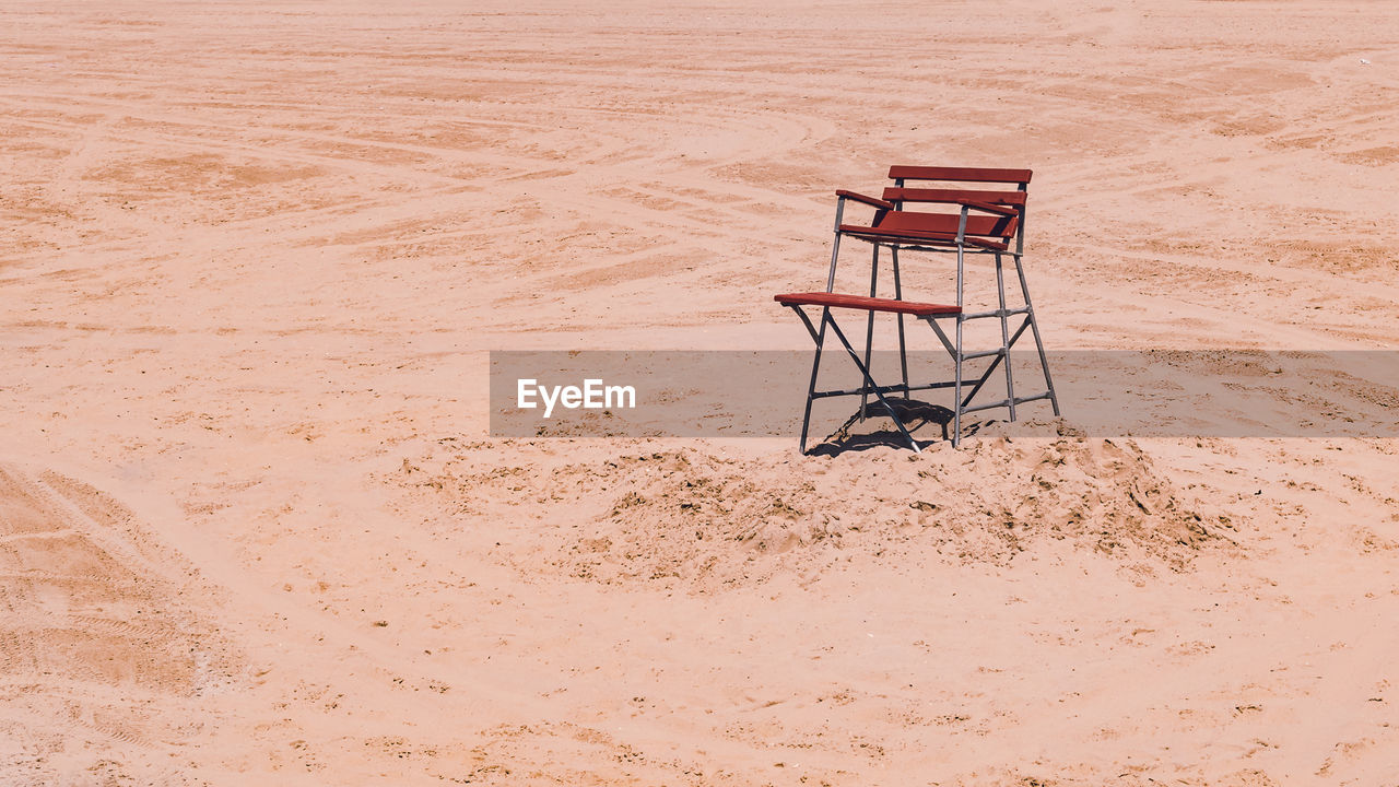 Empty chair on sand at beach