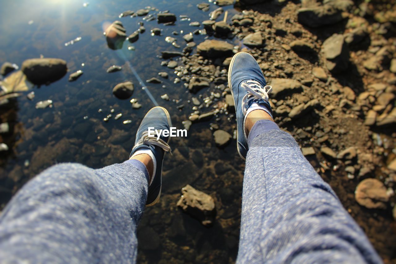 Low section of man wearing shoes over lake