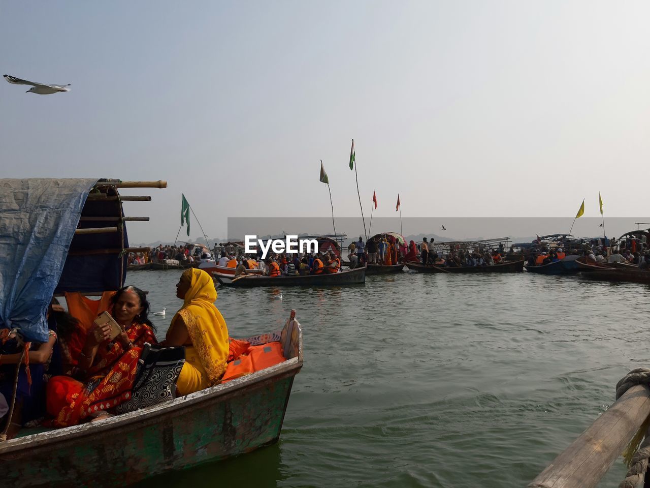 People on boats in sea against clear sky