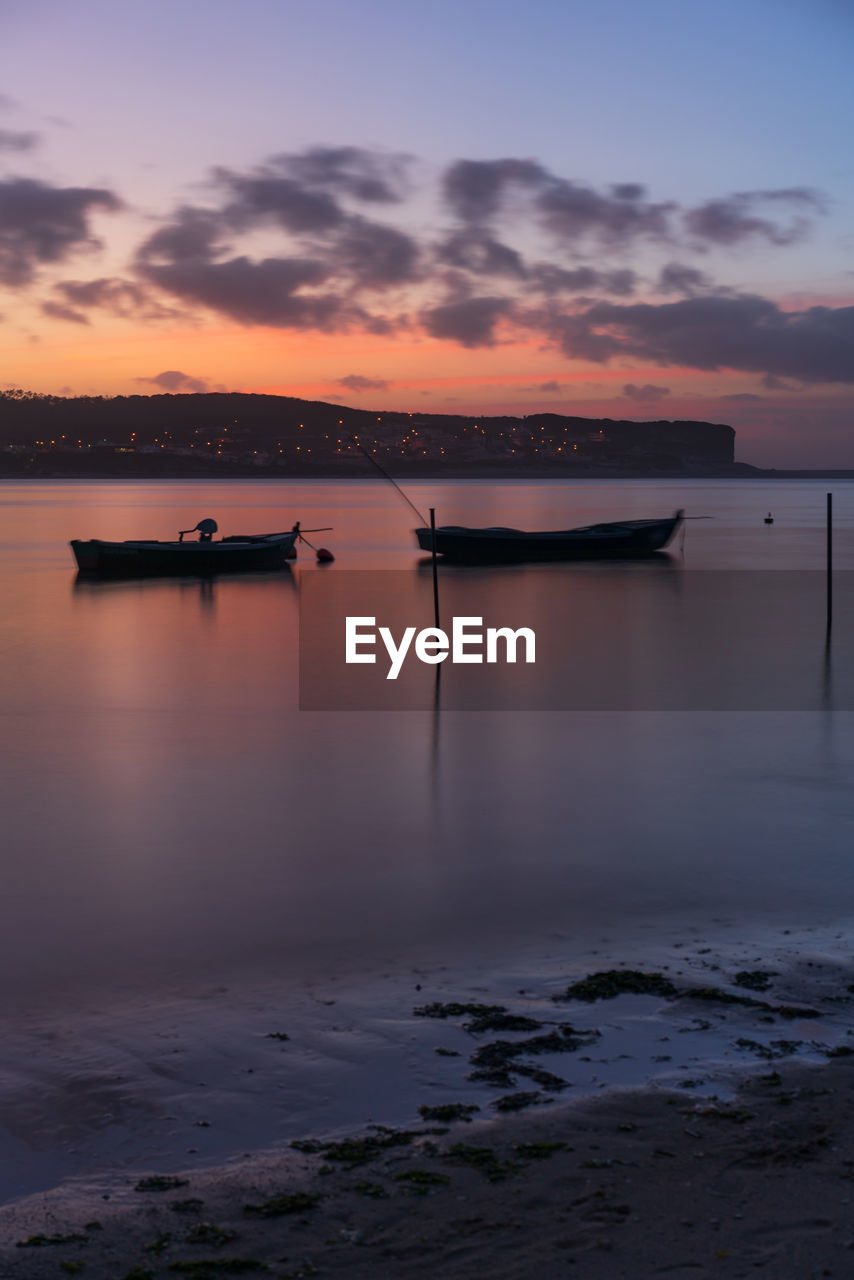 Fishing boats on a river sea at sunset in foz do arelho, portugal