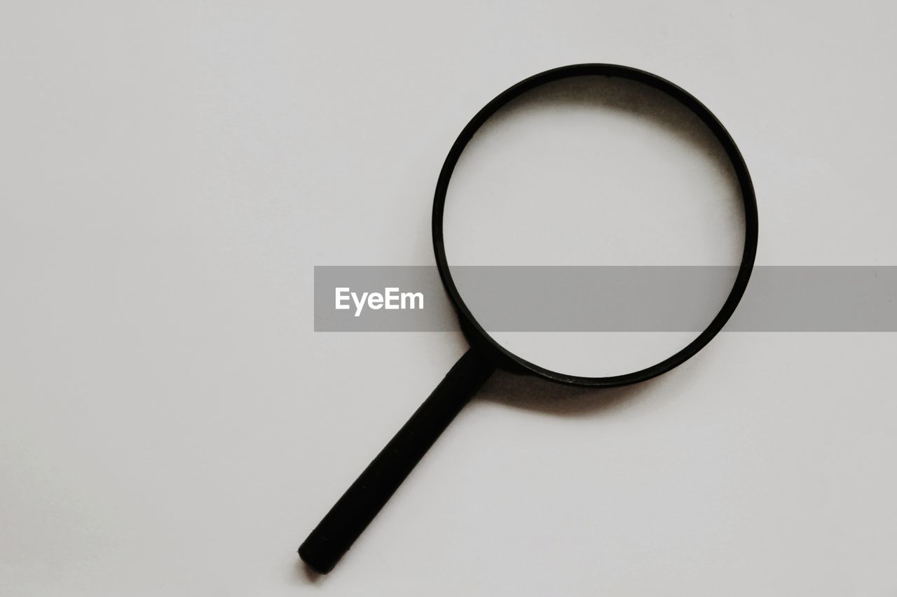 Close-up of magnifying glass against white background