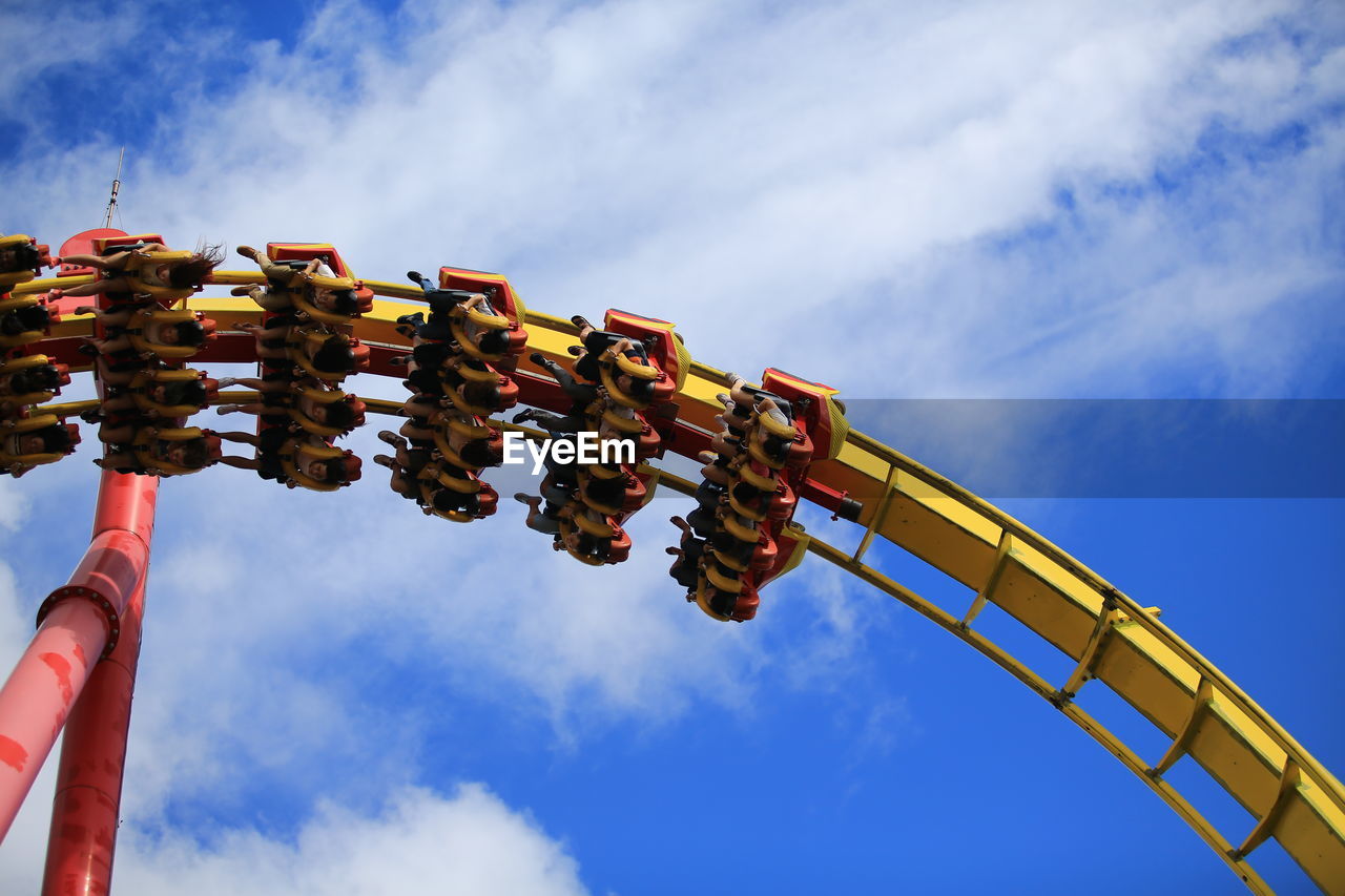 Low angle view of people on amusement ride against blue sky