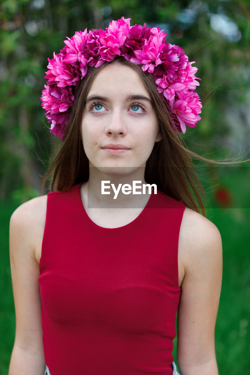 PORTRAIT OF BEAUTIFUL YOUNG WOMAN WITH PINK FLOWER IN MOUTH