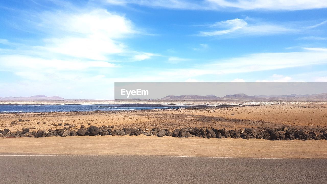 SCENIC VIEW OF SAND DUNE ON BEACH AGAINST SKY