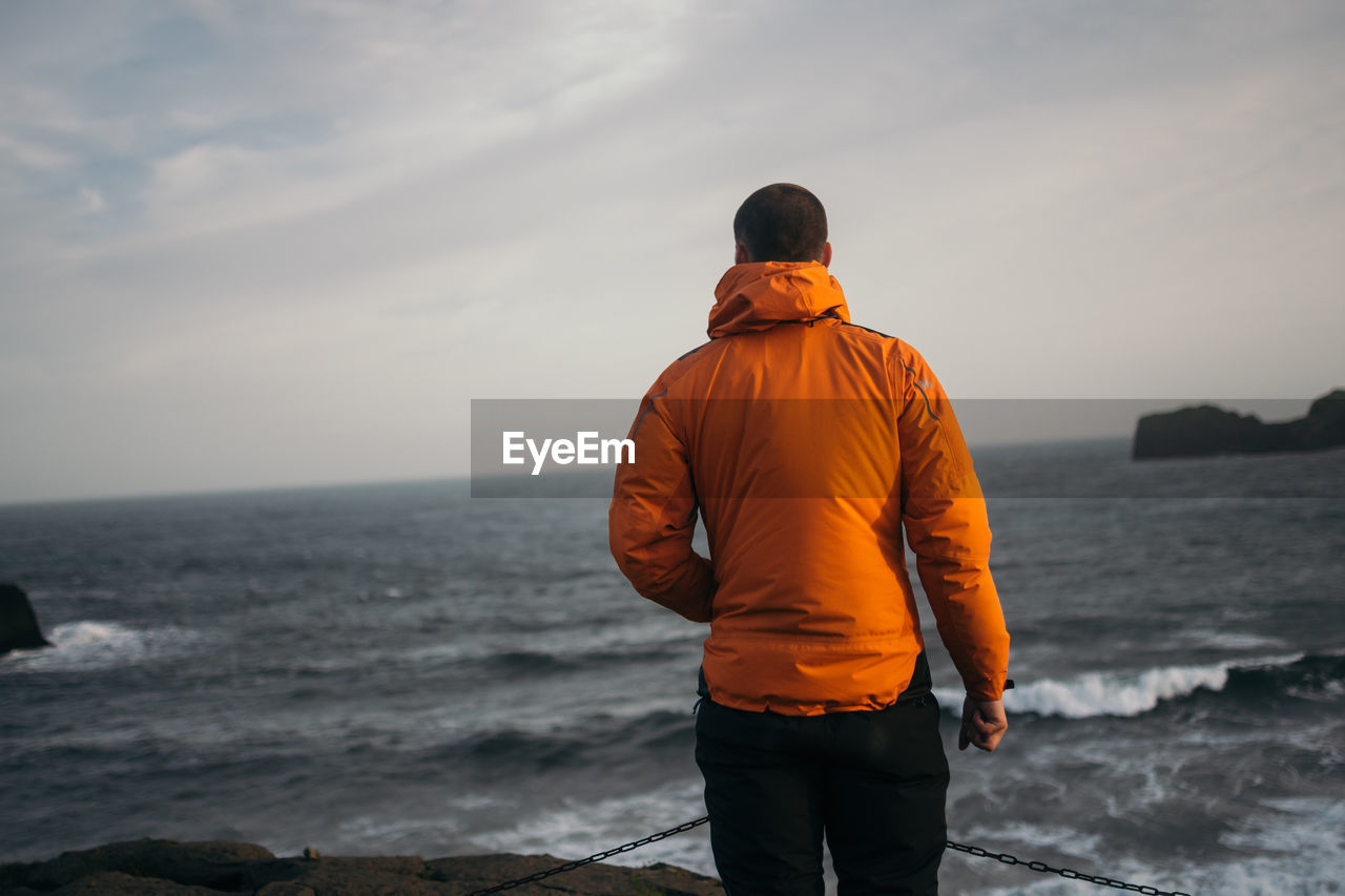 Youngman standing at windy beach of dyrhólaey, iceland