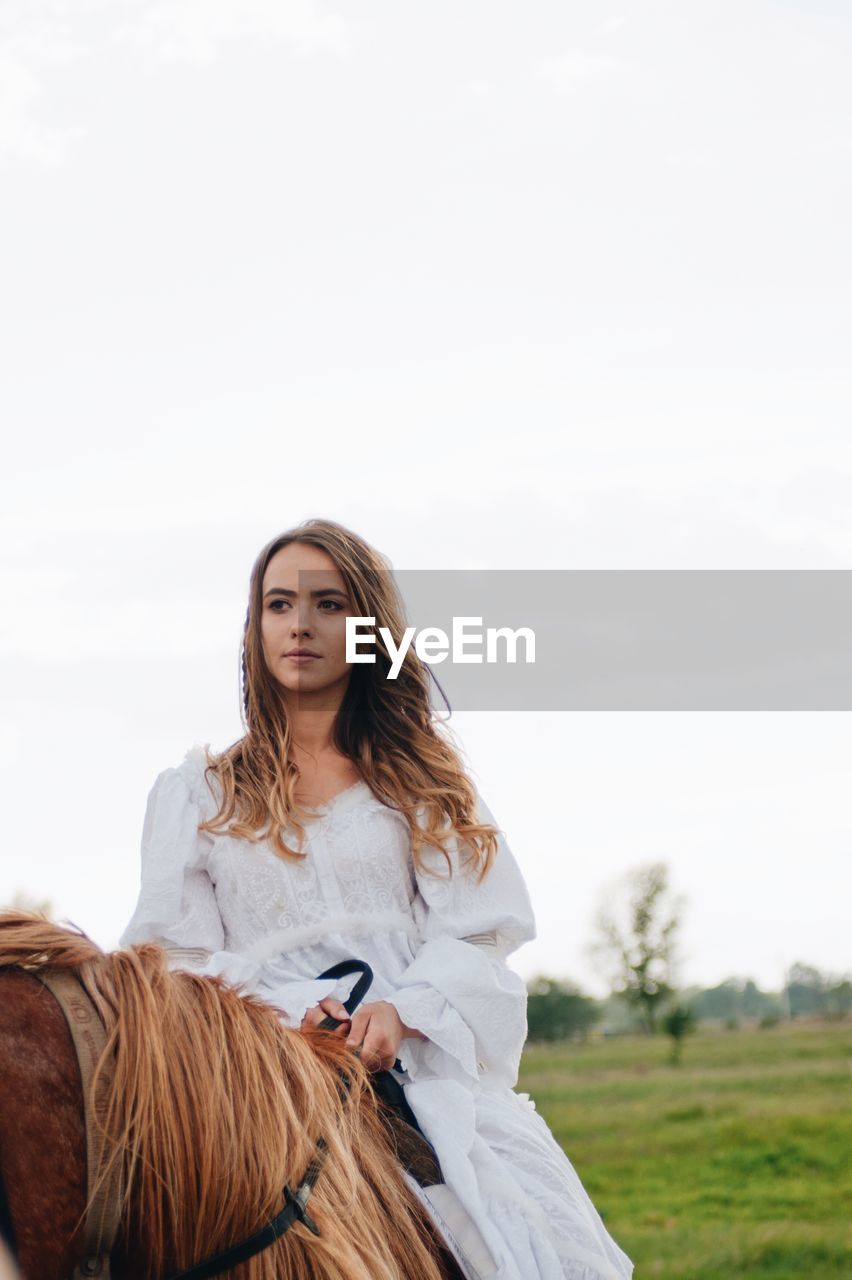 Young woman riding horse on field