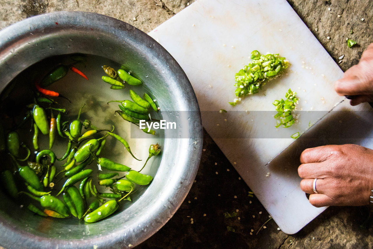 Close-up of hands cutting green chilies