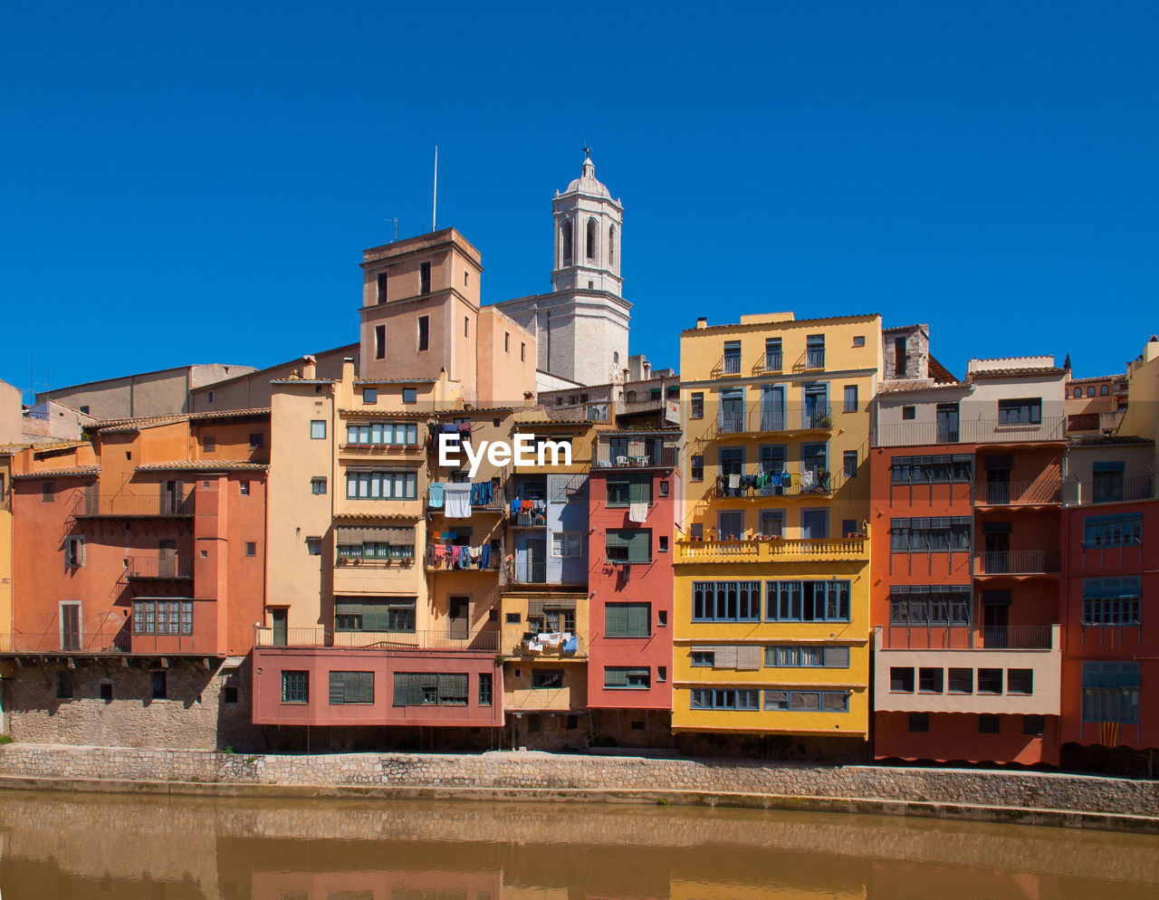 Colorful buildings by river against clear blue sky