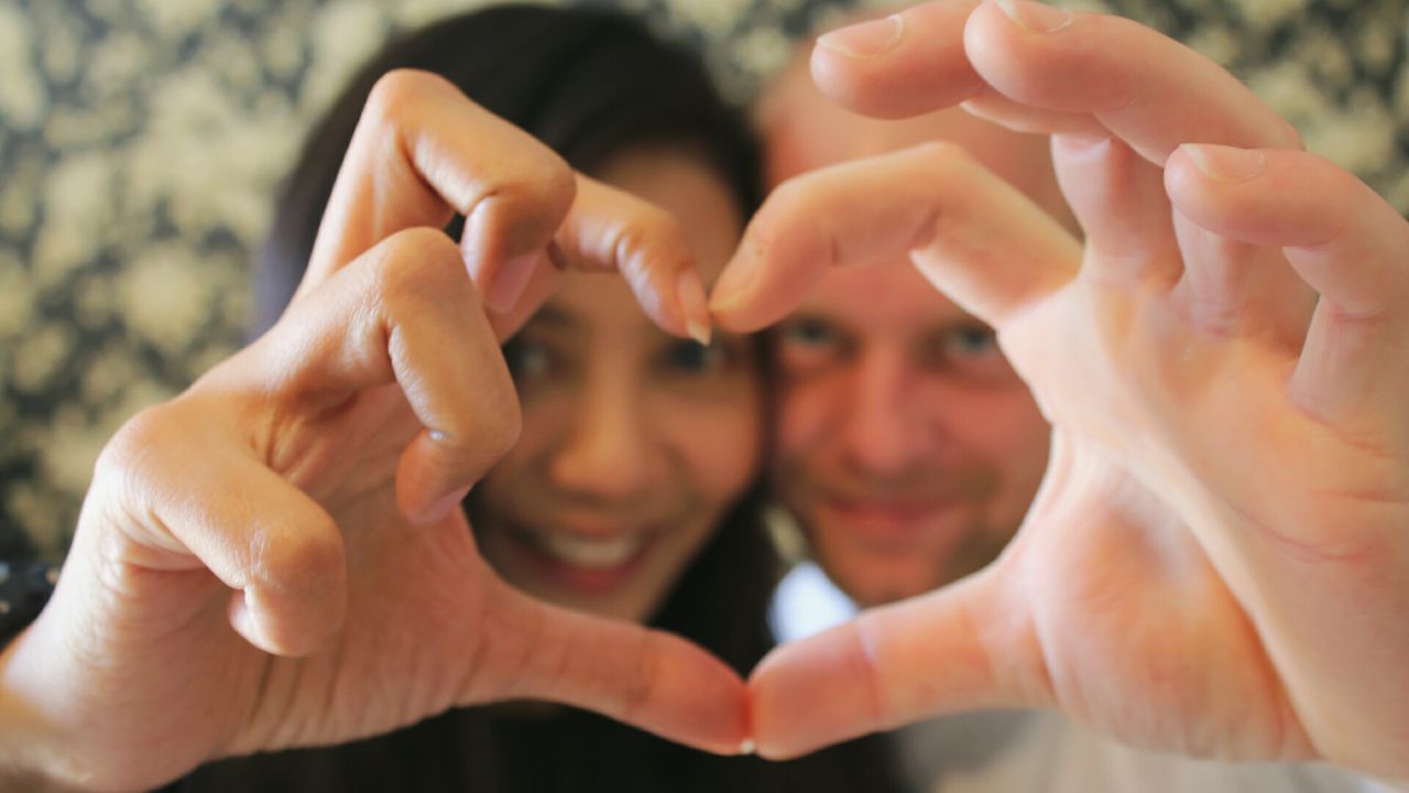 Close-up portrait of couple making heart shape with hands
