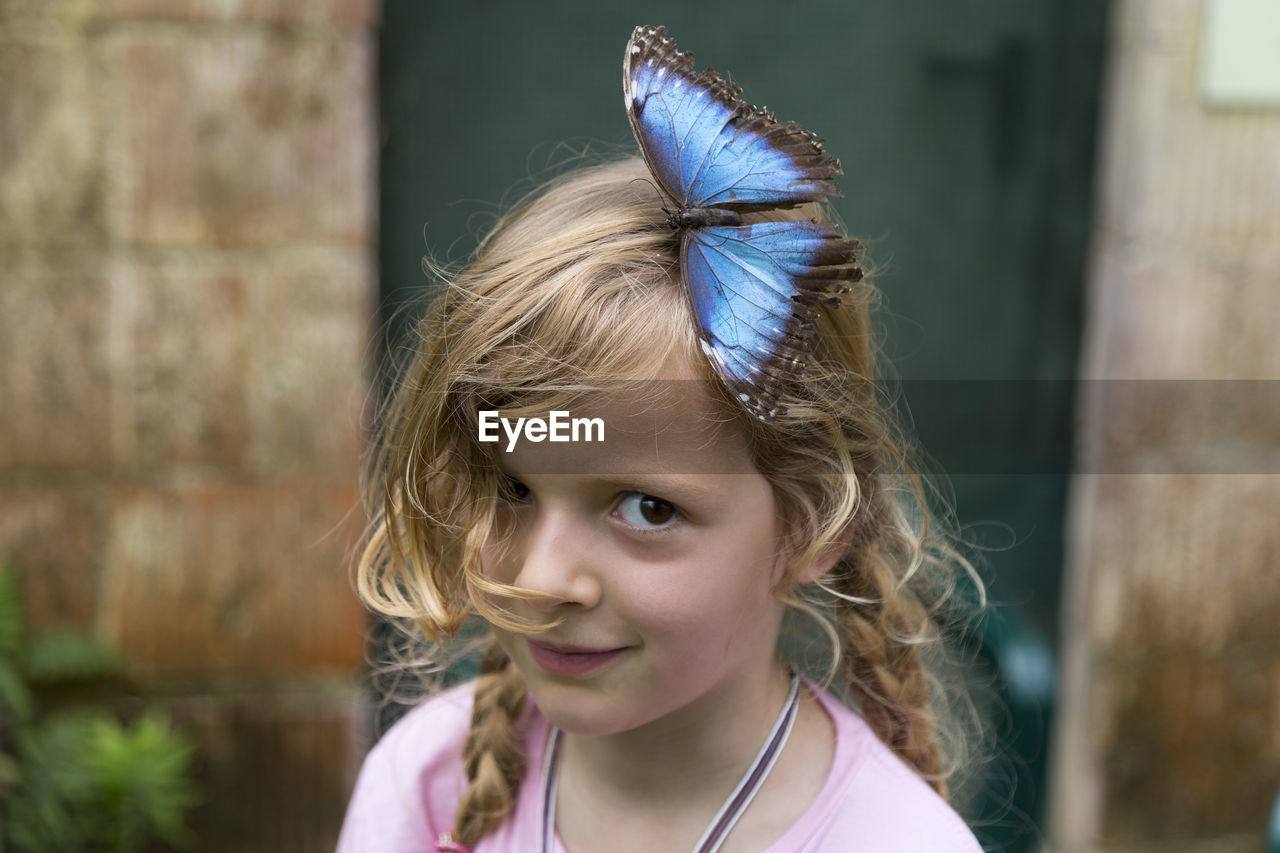 Portrait of smiling girl with butterfly on her head