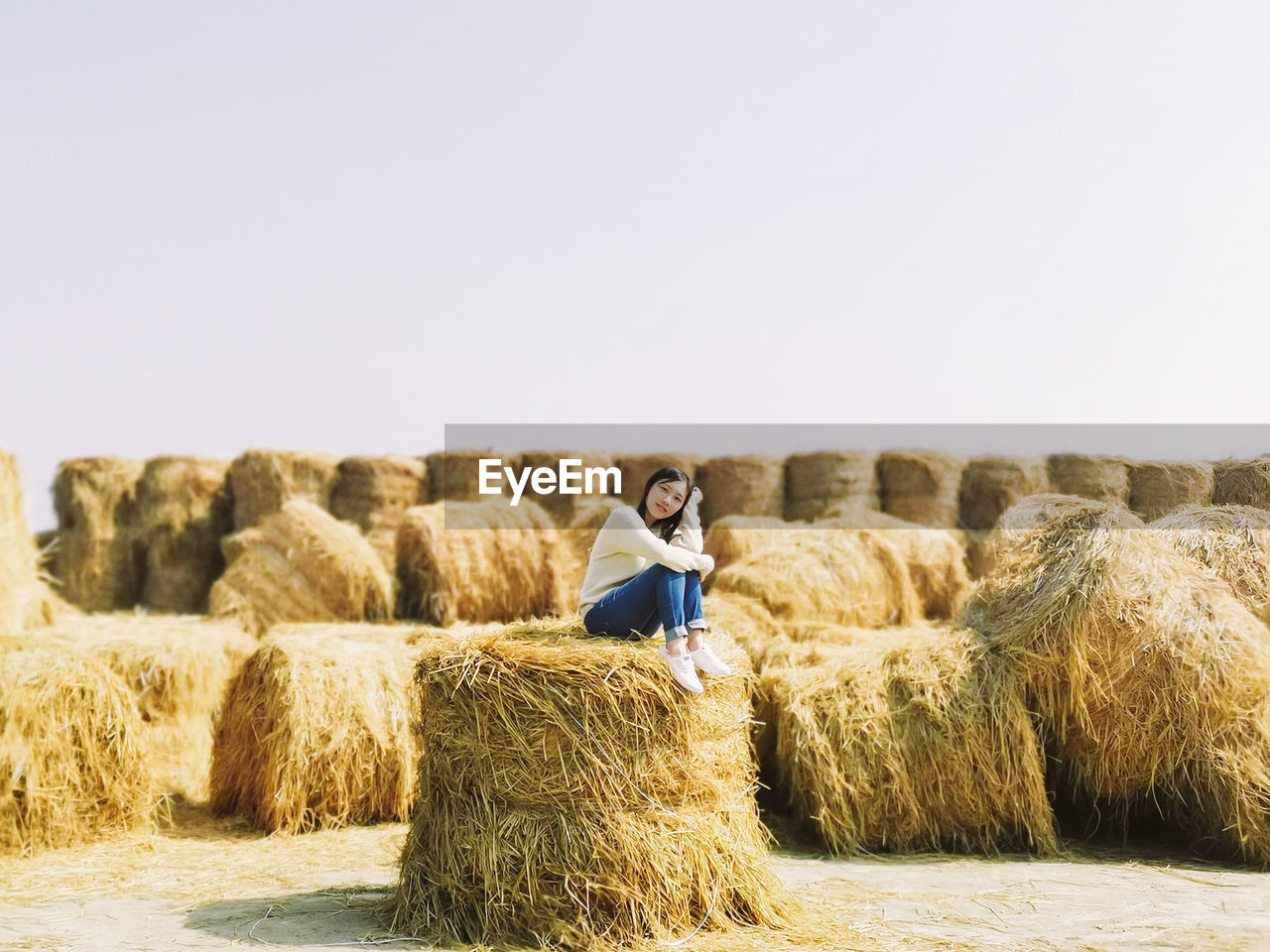 Full length of woman sitting on hay bale