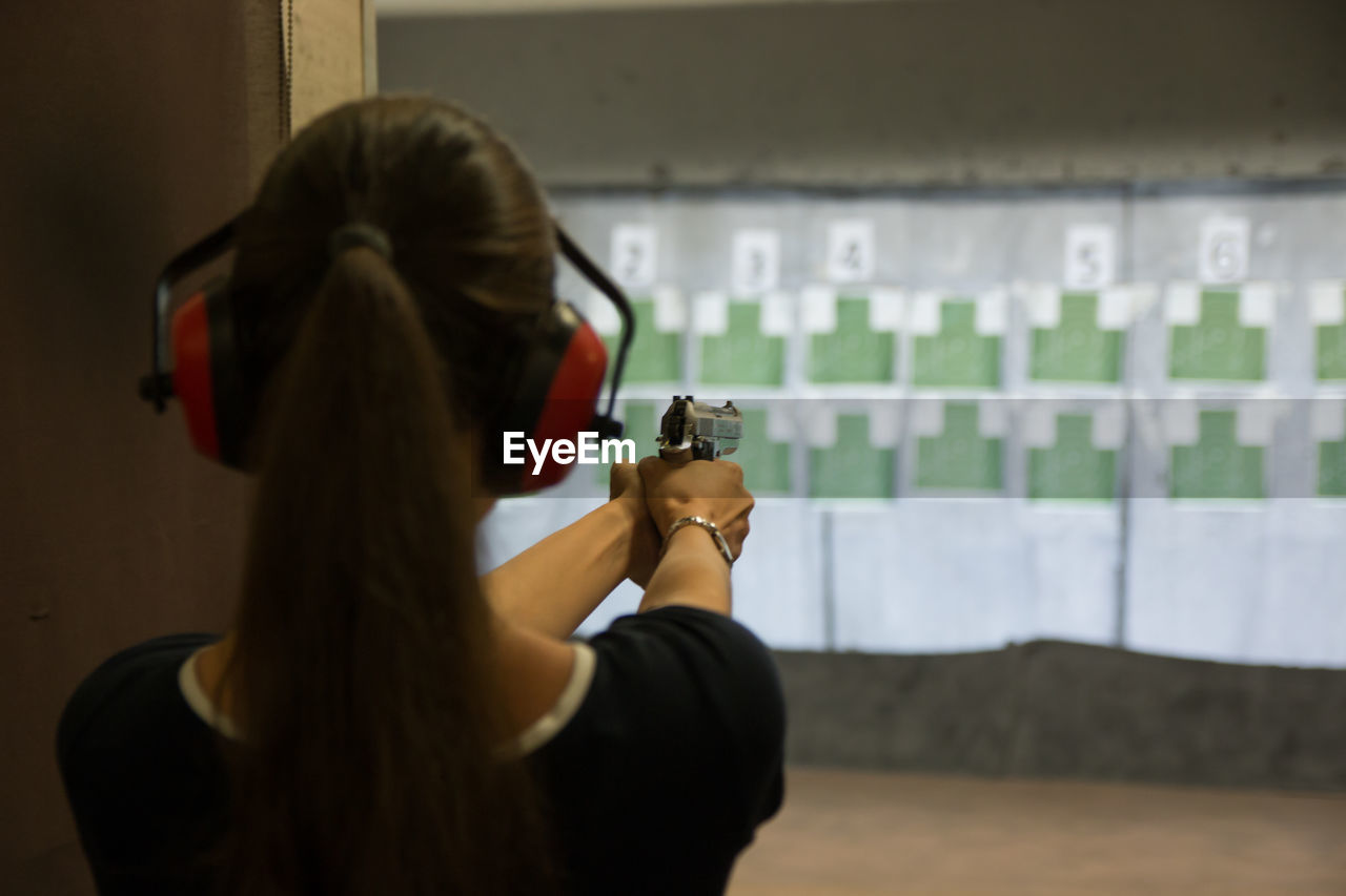 Rear view of woman shooting at target