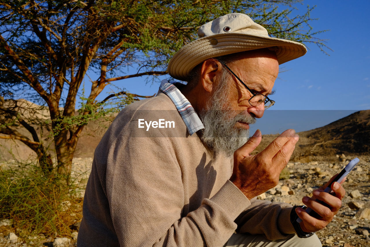 Senior man using mobile phone in the desert 