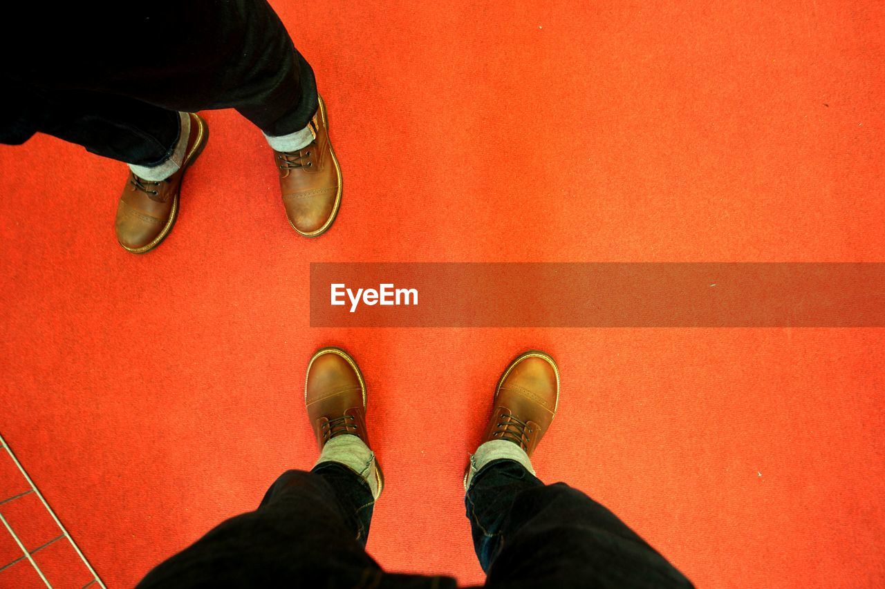 Low section of man standing on red carpet