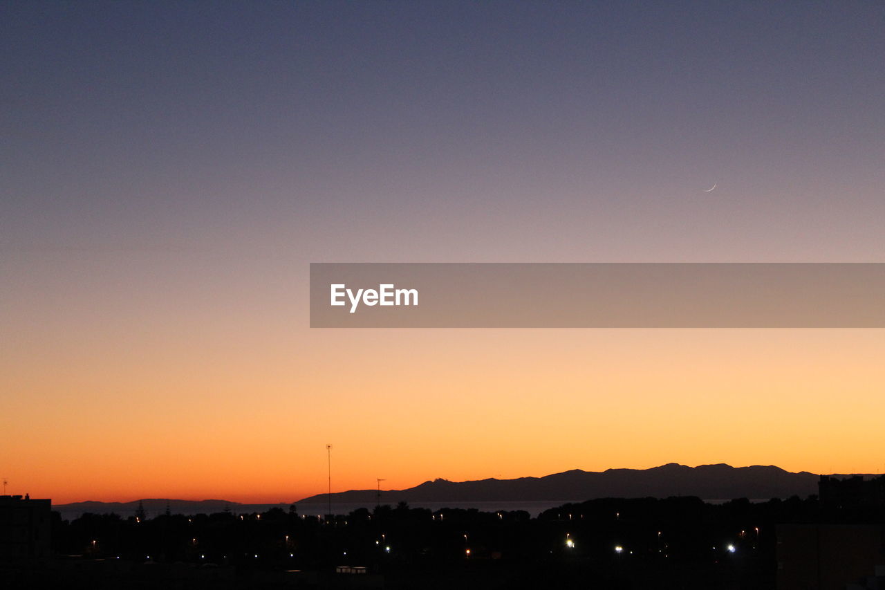 Silhouette buildings against clear sky during sunset