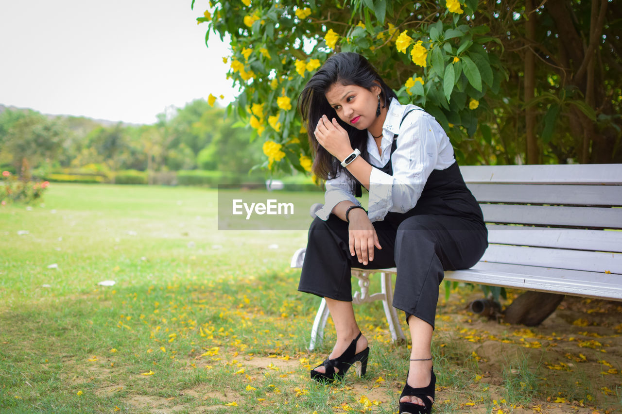 Full length of fashionable young woman sitting on bench