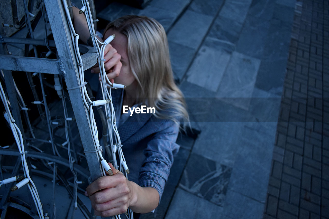 High angle view of woman crouching by gate outdoors