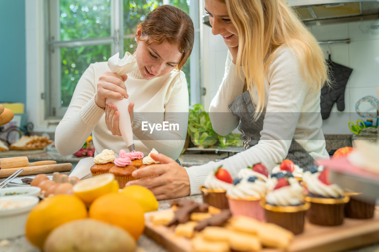 Mother and daughter working together happily to make sweets on holiday.