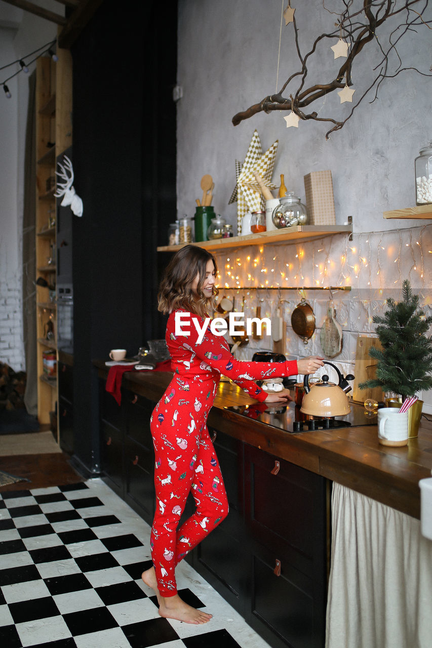 Funny pretty girl in red pajamas having fun on christmas holiday in a cozy indoor house