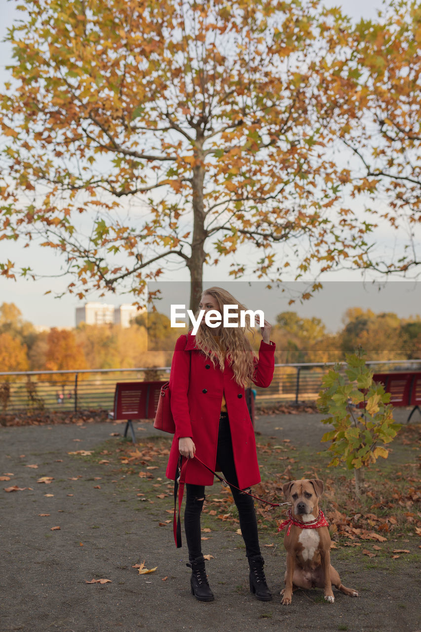 FULL LENGTH OF MAN WITH DOG STANDING AGAINST TREES