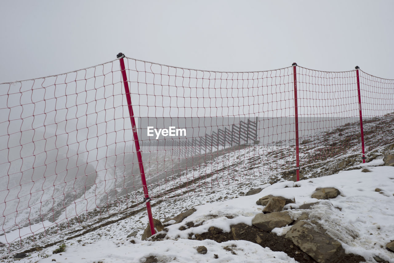 Red mesh in the mountains. restriction in the snowy mountains. low cloudy sky. fog. 