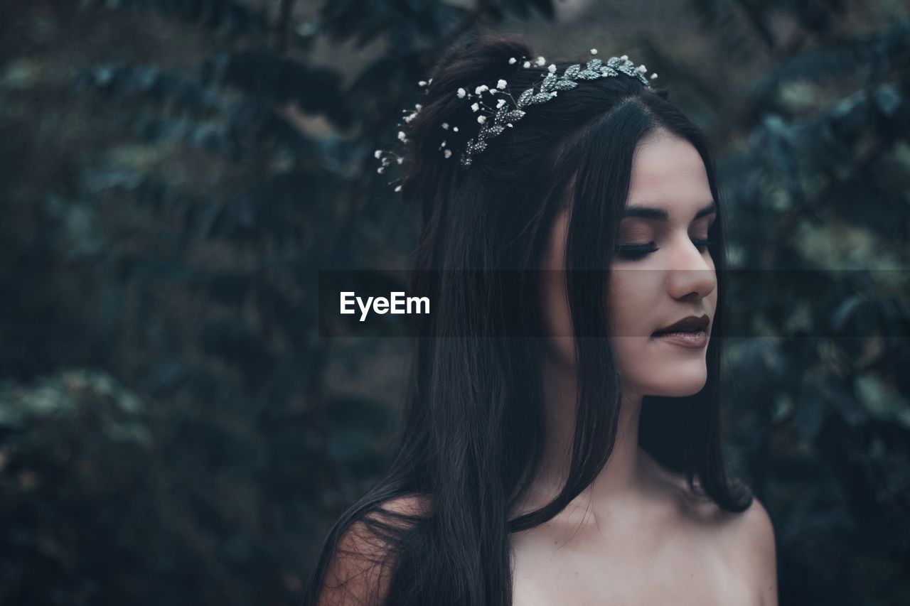 Beautiful young woman wearing tiara against plants