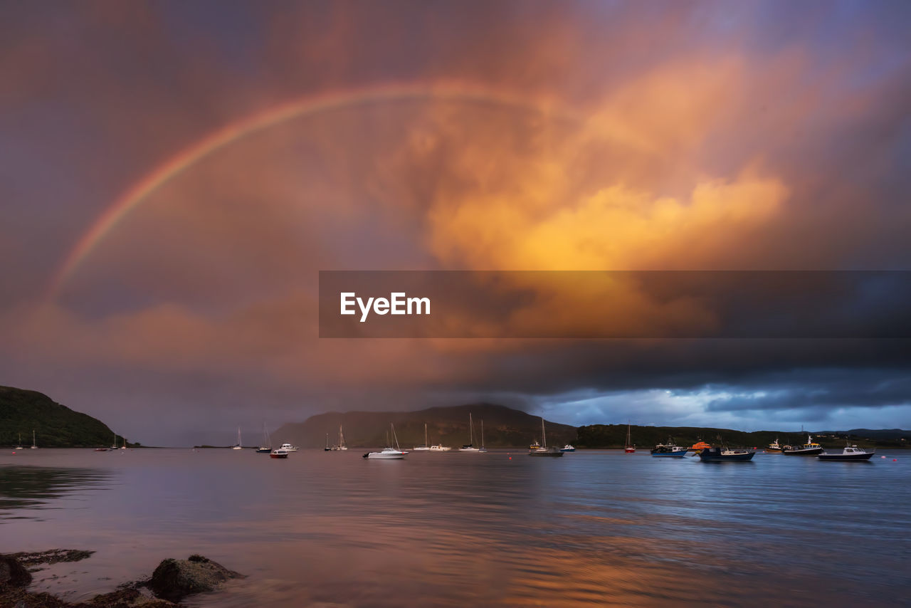 RAINBOW OVER SEA AGAINST SKY DURING SUNSET