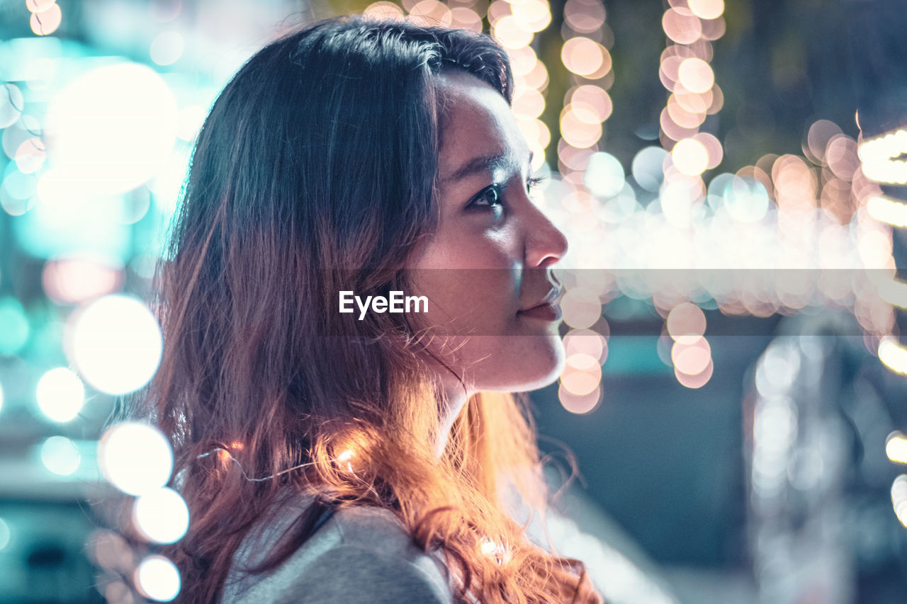 Close-up of young woman amidst illuminated lights