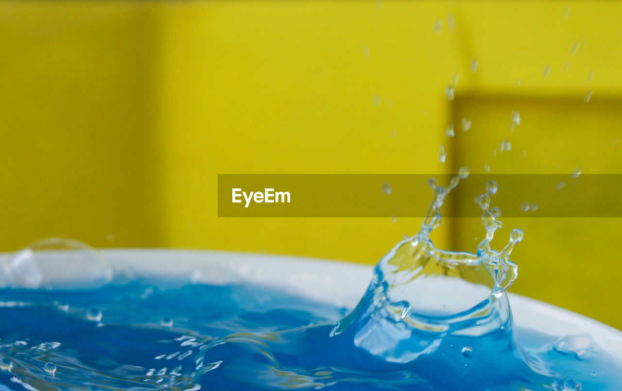 Close-up of water splashing against yellow wall