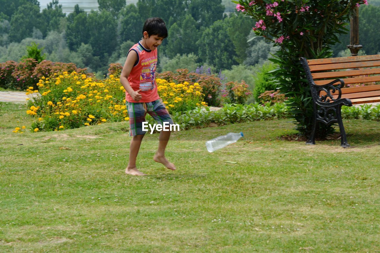 Full length of boy playing with bottle on field at park