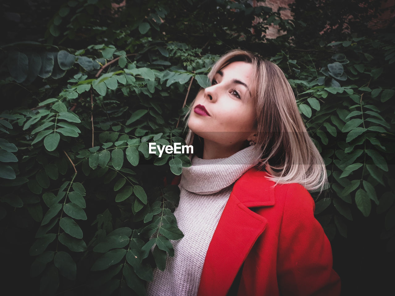 Thoughtful young woman looking away by plants