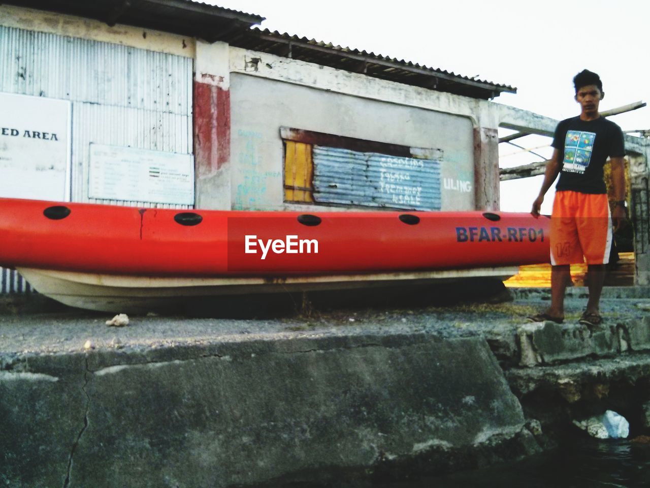 MAN STANDING BY BOAT