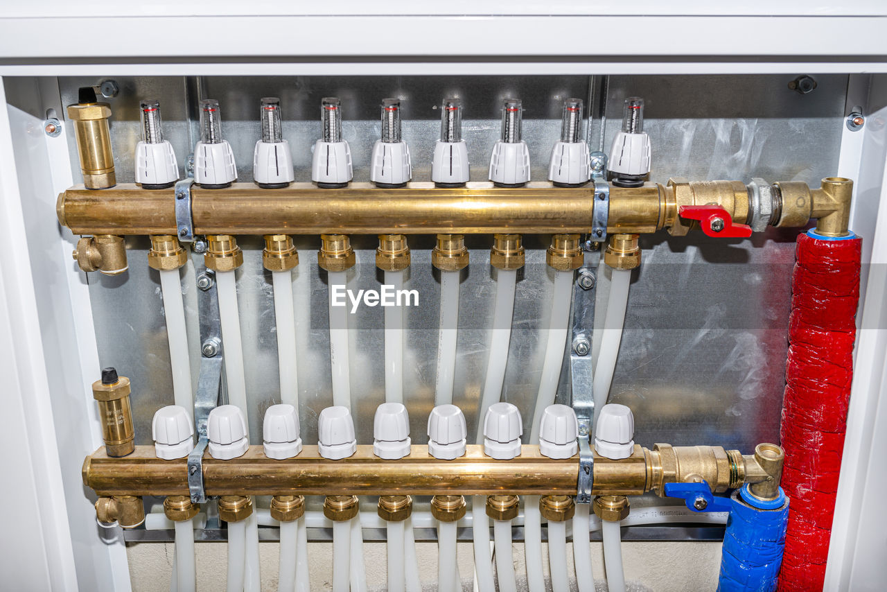 New manifold of underfloor heating system, plastic pipes and valves visible, serving nine circuits.