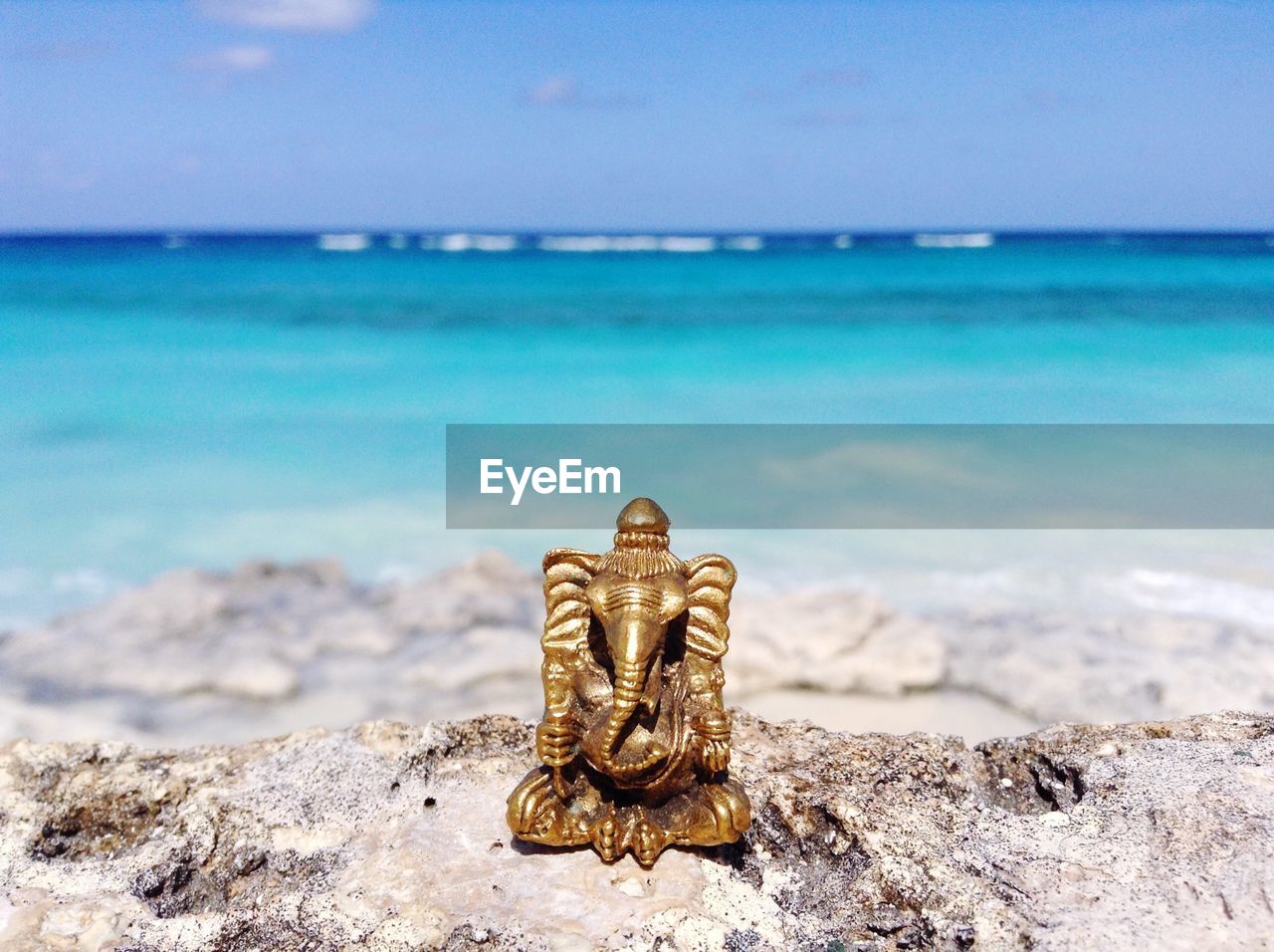 Close-up of ganesha statue on rock by sea against sky