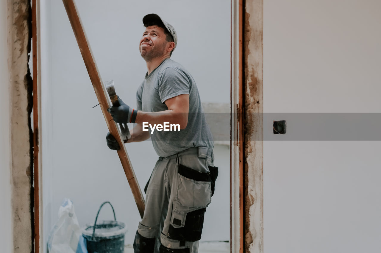 A man working with a crowbar in a doorway.